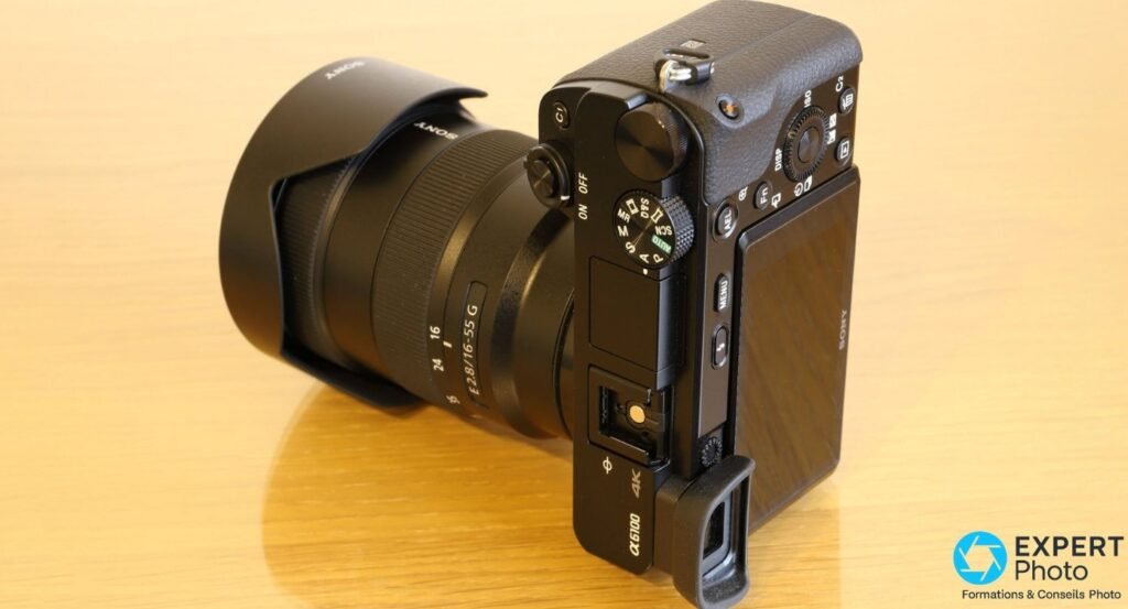 Sony Alpha 6100 vu de dessus en plongée, commandes et molette des modes visibles, objectif Sony E 16-55 mm f/2,8 G.
