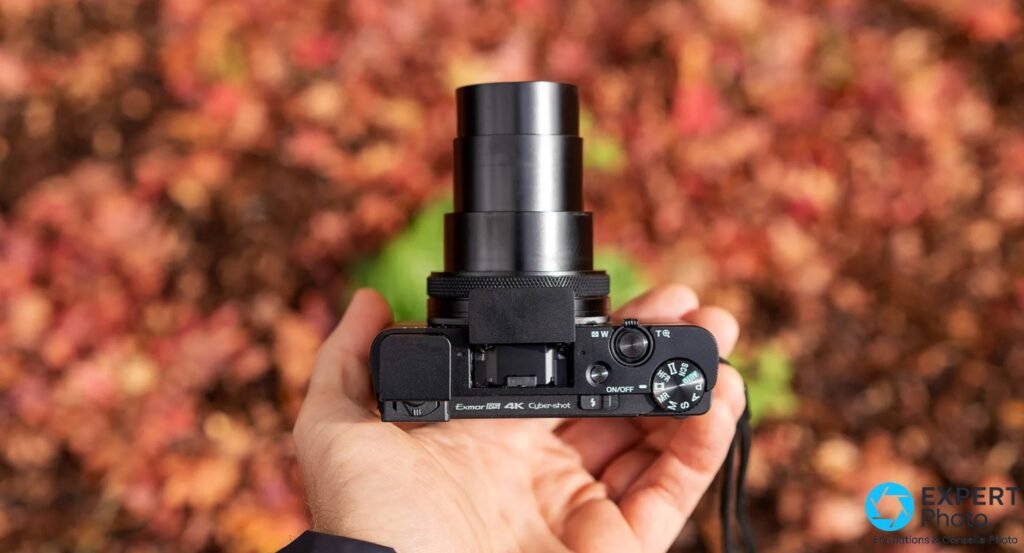 Sony RX100 VII vu du dessus, zoom sorti en position téléobjectif, marquage Exmor RS 4K Cyber-shot visible, tenu en main 