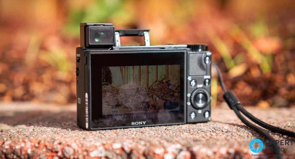 Sony RX100 VII vu de dos, viseur électronique rétractable déployé, écran LCD actif avec données d'exposition, posé en extérieur 