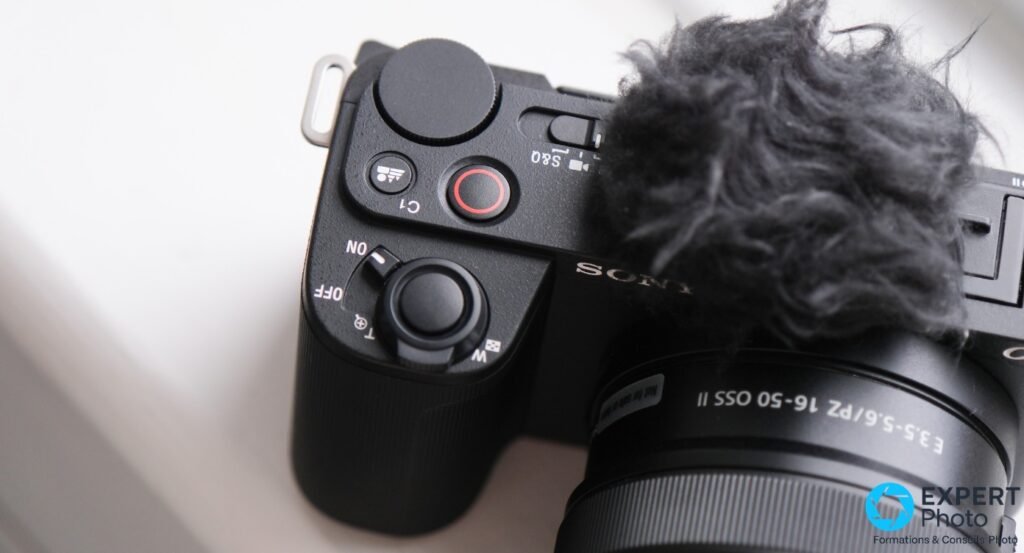 Gros plan du dessus du Sony ZV-E10 II : molette, bouton REC, logo SONY et bonnette anti-vent en fourrure