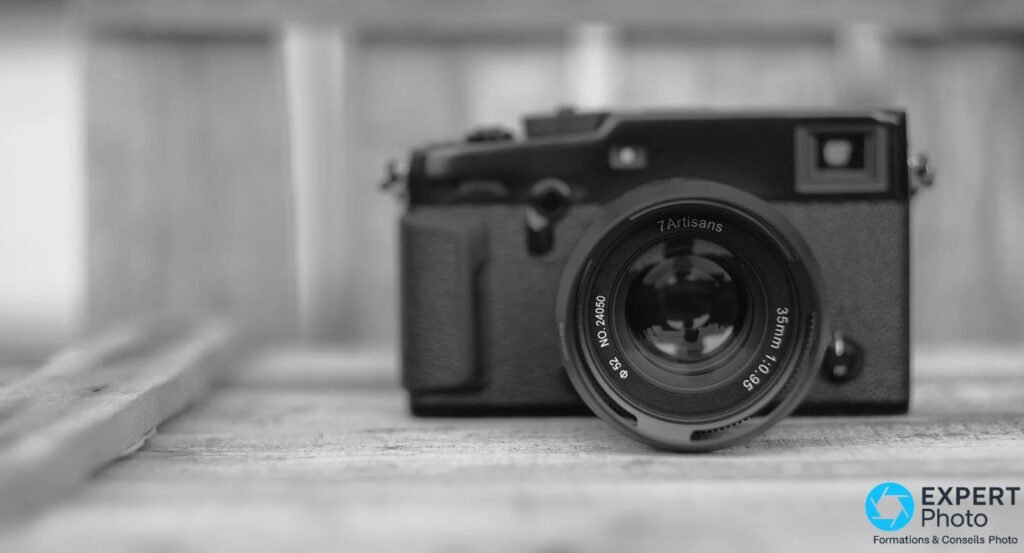 7Artisans 35mm f/0.95 face avant sur boîtier compact noir, inscriptions 7Artisans et NO.24050 lisibles, photo N&B fond bois