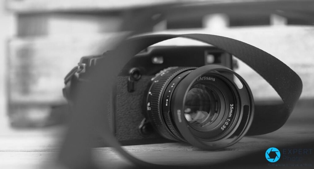 7Artisans 35mm f/0.95 avec pare-soleil, vue face, sangle noire en arc, boîtier compact flou, bague 7Artisans lisible