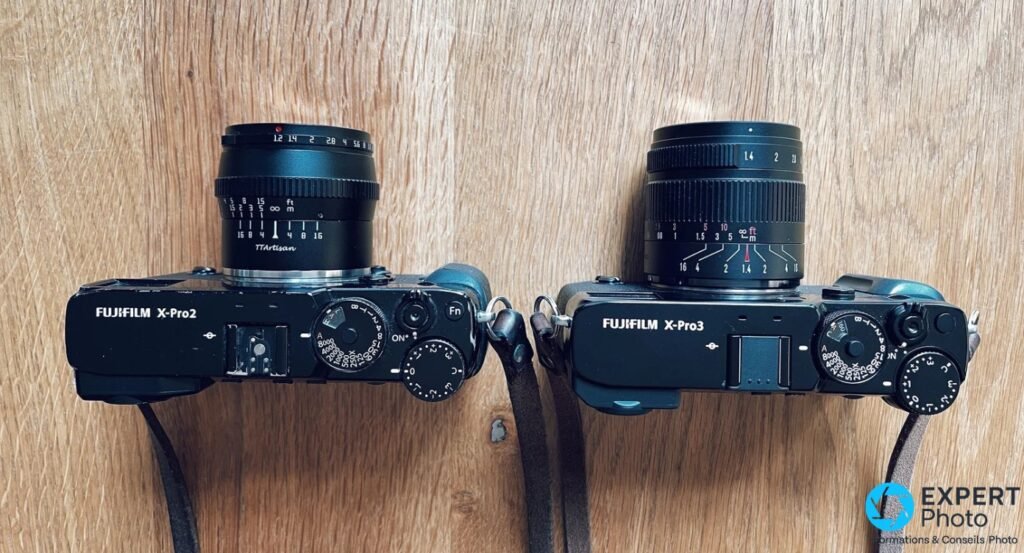 Fujifilm X-Pro2 (objectif TTArtisan) et X-Pro3 (objectif 7Artisans 55mm f/1.4) côte à côte sur bois, vus de dessus