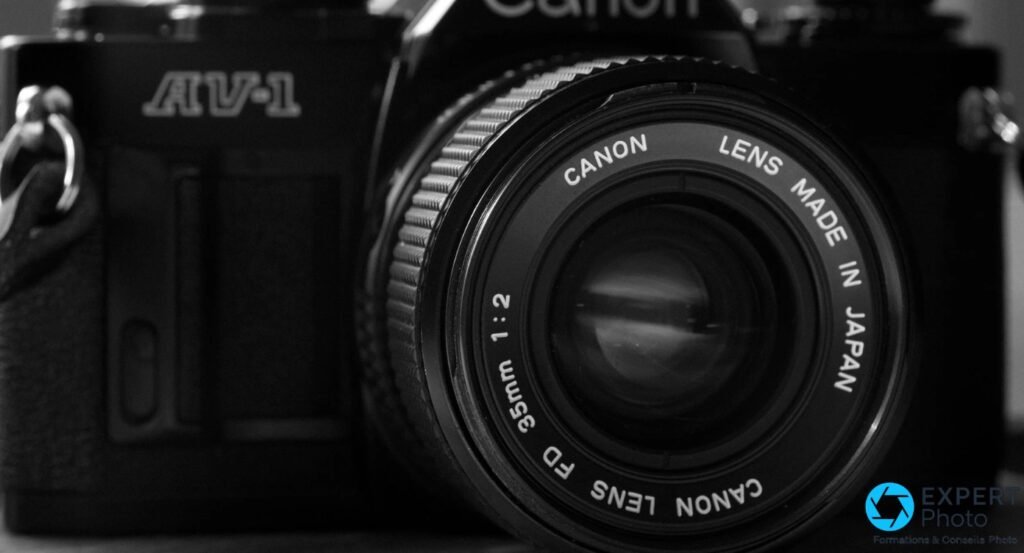 Canon New FD 35mm f/2 monté sur reflex argentique Canon AV-1, gros plan face avant en noir et blanc. 