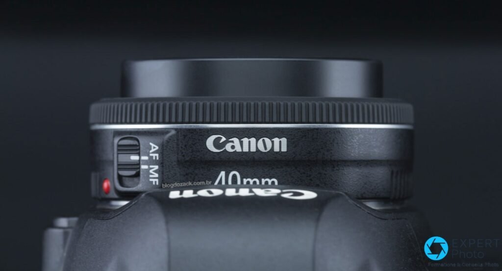 Profil serré Canon EF 40mm f/2.8 STM : gravures Canon et 40mm lisibles, commutateur AF/MF, point rouge EF visible