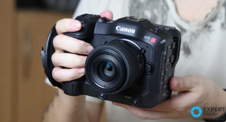 Test Canon C70 : documentaire, corporate et multicam — pourquoi ces usages tiennent encore Canon EOS C70 tenu à deux mains, objectif compact monté sur monture RF, boutons AF Lock et REC visibles