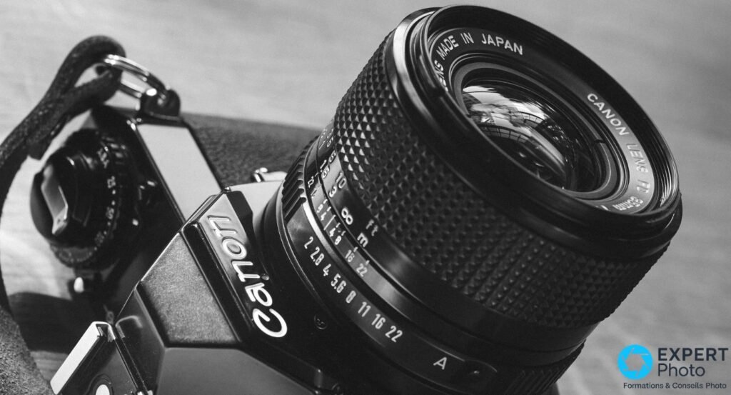 Canon New FD 35mm f/2 en profil, bagues de diaphragme et de mise au point visibles, rendu noir et blanc. 