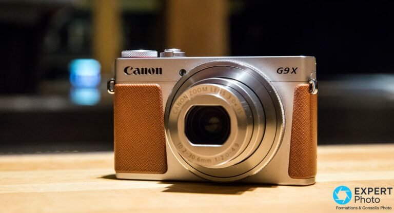 Canon PowerShot G9 X avis: ce qu’il est vraiment en 2026 Canon PowerShot G9 X argenté vue face avant, objectif zoom rétracté, revêtement caramel, posé sur table en bois