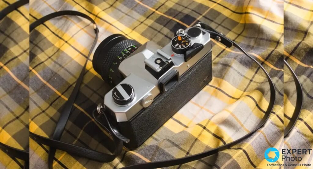 Fujica AZ-1 en vue 3/4 plongeante avec sangle noire, bague objectif avec graduations colorées et molette des vitesses