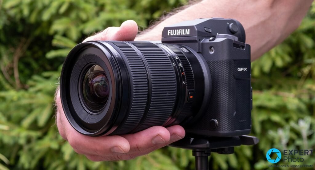 Fujifilm GF 20-35mm f/4 R WR sur boîtier Fujifilm GFX tenu en main, vue 3/4 avant, logos FUJIFILM et GFX lisibles