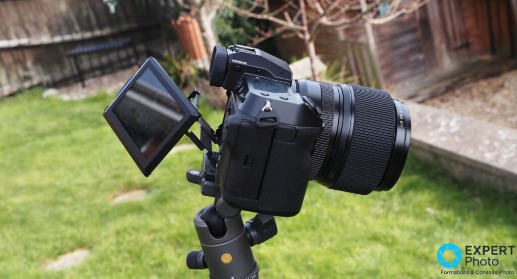 Fujifilm GFX 100S profil gauche, écran articulé déployé vers la gauche, objectif Fujinon GF WR monté, sur trépied 