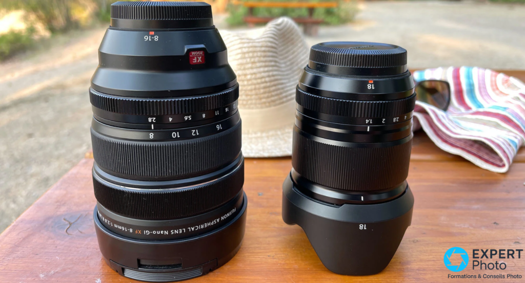 Fujifilm XF 8-16mm f/2.8 R LM WR posé à gauche côté à côté avec un second objectif Fujifilm marqué 18, sur table en bois