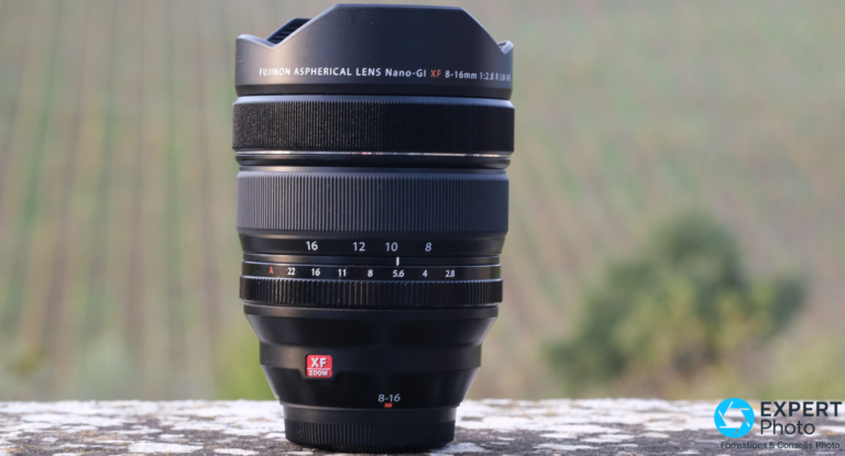 Fujifilm XF 8-16mm f/2.8 R LM WR de face sur pierre, pare-soleil monté, bagues de mise au point et d'ouverture visibles