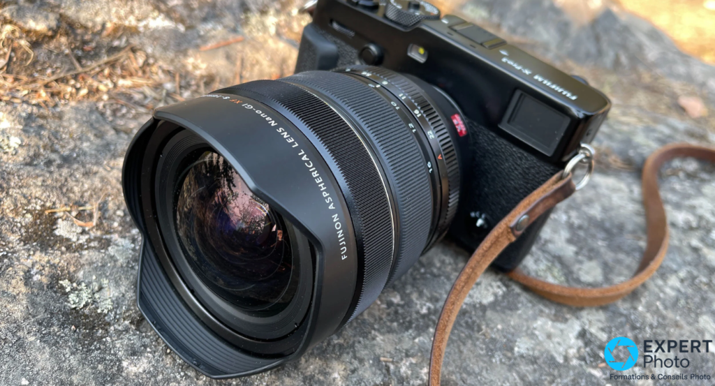  Fujifilm XF 8-16mm f/2.8 R LM WR monté sur Fujifilm X-Pro3 sur roche, vue 3/4 avant, bonnette et élément avant nets