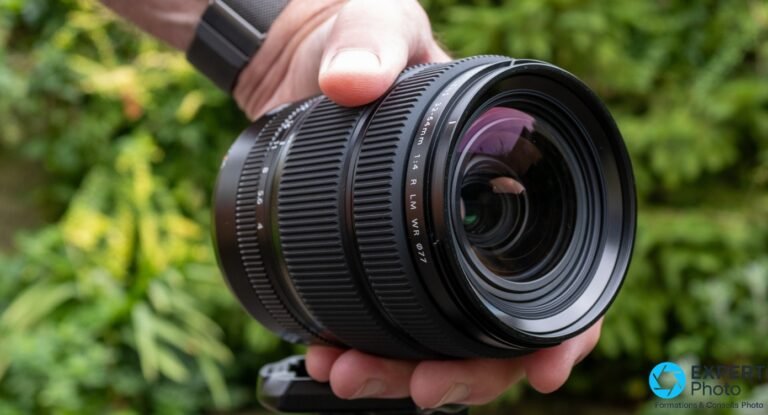 Fujifilm GF 32-64mm F4 : pour les photographes GFX en paysage, studio et architecture Fujinon GF 32-64mm F4 R LM WR tenu en main, vu de face, élément frontal ⌀77 et bagues de mise au point visibles