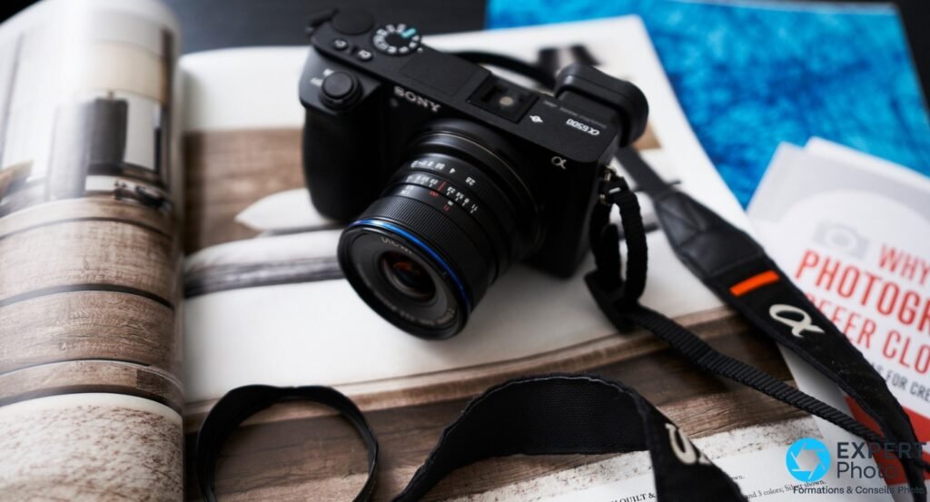 Laowa 9mm f/2.8 Zero-D sur Sony α6500 posé sur livre ouvert, angle 3/4 avant gauche, bague bleue visible