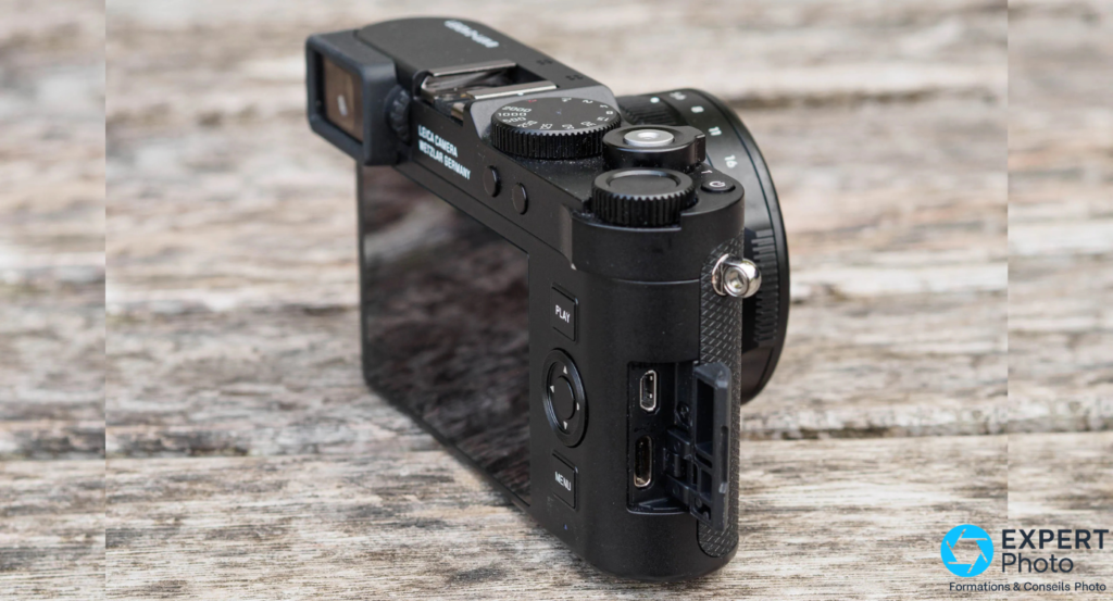 Leica D-Lux 8 profil droit, trappe connectique ouverte avec ports USB visibles, boutons PLAY MENU apparents sur le dos