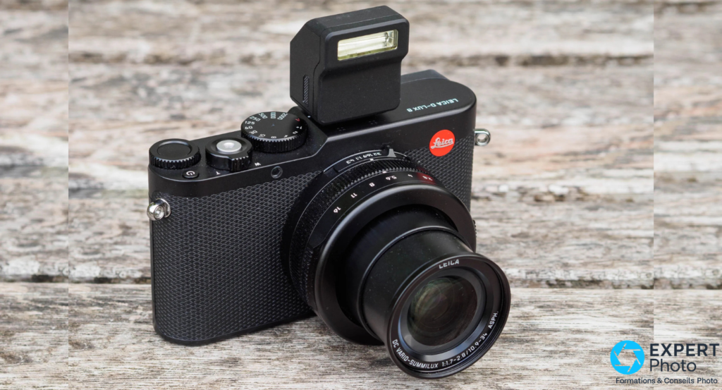 Leica D-Lux 8 noir avec flash externe sur griffe, objectif Vario-Summilux f/1,7-2,8 étendu, logo Leica rouge visible