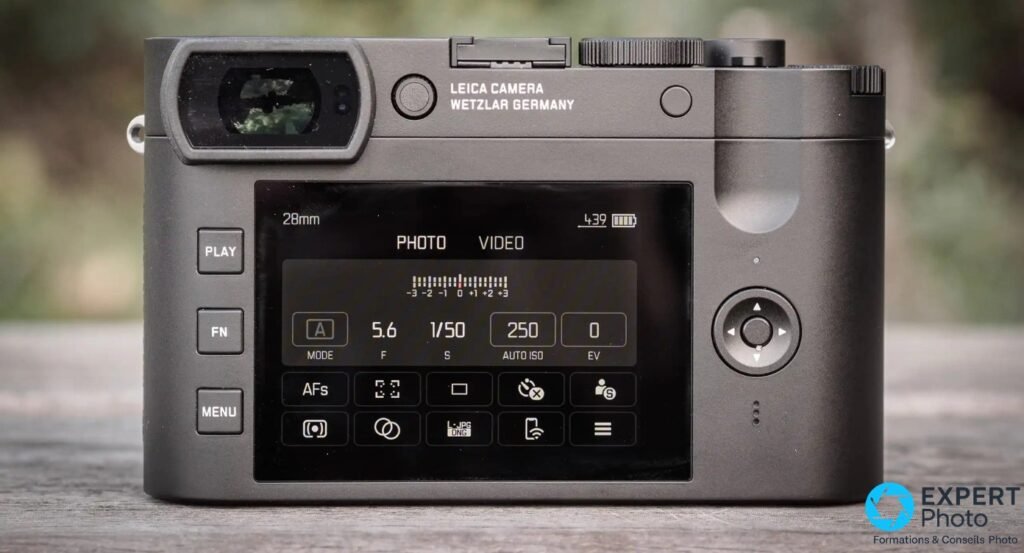 Dos du Leica Q2 Monochrom avec écran LCD allumé affichant les réglages de prise de vue, boutons PLAY FN MENU.
