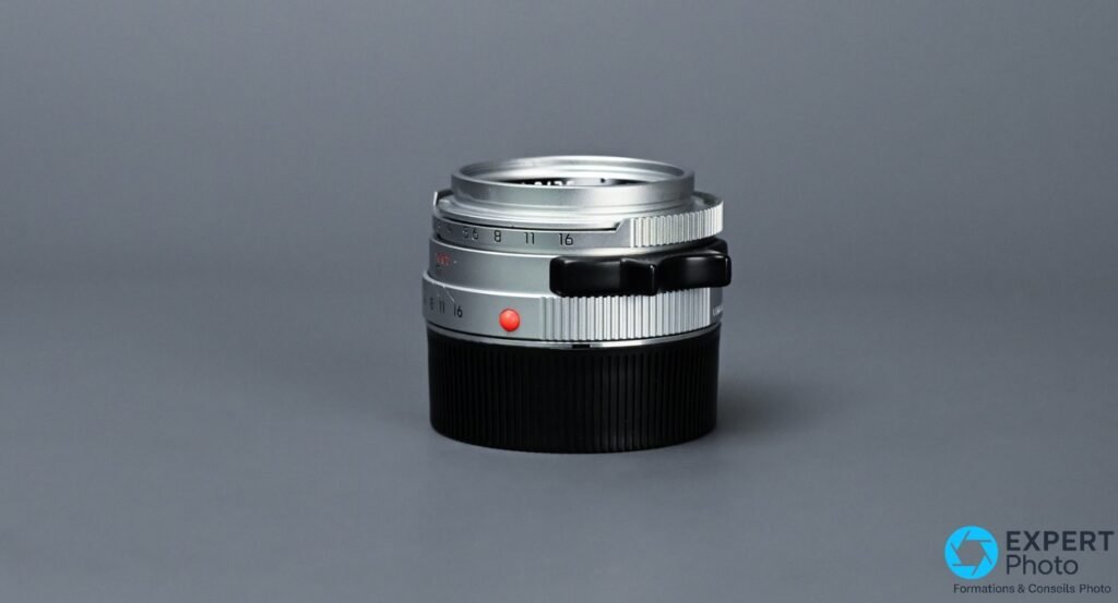  Leica Summicron-M 35mm f/2 IV chrome, vue profil 3/4 arrière droit, patte de mise au point noire et graduation diaphragme f/5.6–f/16 