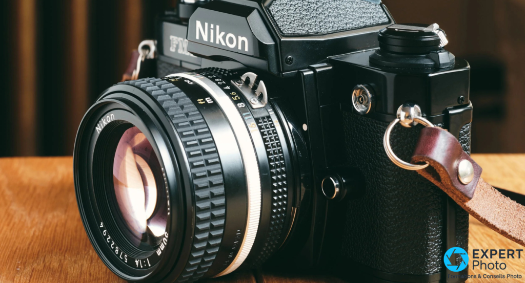 Gros plan sur l'objectif Nikkor 50mm f/1.4 : bague de mise au point moletée et verre avant avec reflet, monté sur reflex Nikon