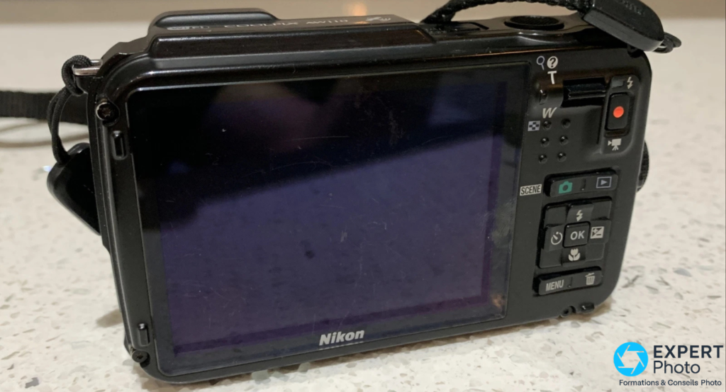 Dos du Nikon Coolpix AW110 avec écran LCD éteint, boutons SCENE, OK, MENU et déclencheur vidéo rouge
