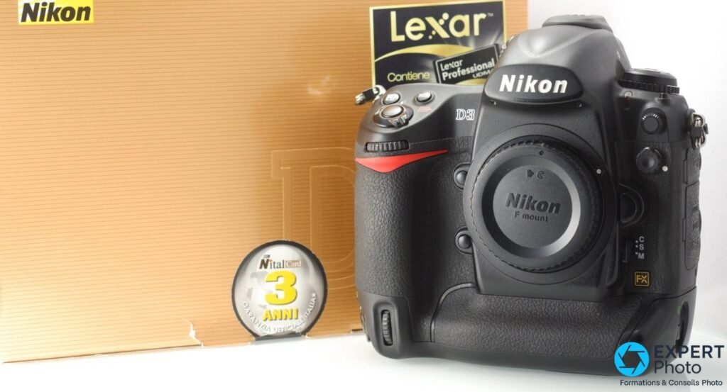 Nikon D3 boîtier reflex noir vue 3/4, cache monture Nikon F mount, boîte carton et emballage Lexar en arrière-plan