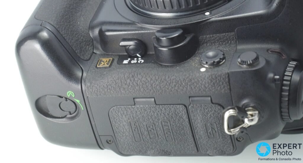 Profil droit Nikon D3, deux trappes slots CompactFlash, badge FX doré, sélecteur rafale, anneau sangle métal