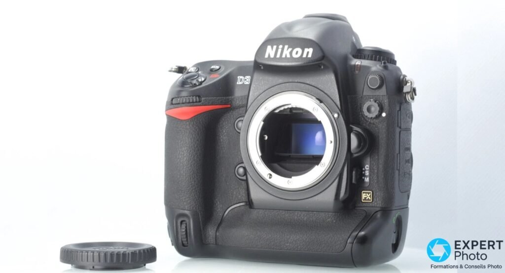 Nikon D3 vue 3/4 gauche, monture ouverte, capteur FX plein format à reflet bleu visible, cache monture posé devant le boîtier
