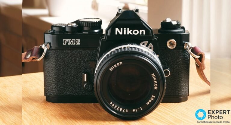 Nikon FM2n avis : ce que vaut vraiment ce reflex mécanique en occasion Nikon FM2n noir de face avec objectif Nikon Nikkor 50mm f/1.4 monté, posé sur une table en bois, sangle cuir brun