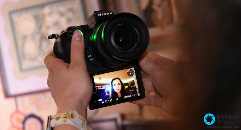  Nikon Z50 vu de dos, écran orientable déplié retourné face avant, affichant un portrait femme en live view avec indicateurs exposition 