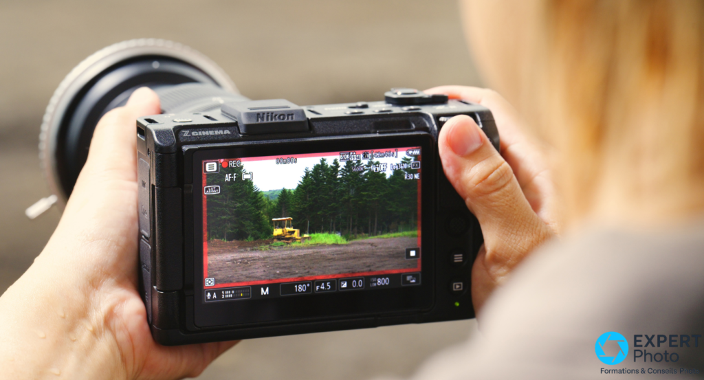 Nikon ZR en enregistrement 6K R3D NE, écran arrière actif avec bordure rouge REC, tenu à deux mains 