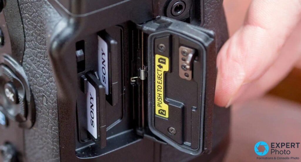 Gros plan sur le double slot SD de l'Olympus E-M1X, deux cartes Sony insérées, étiquette « PUSH TO EJECT » et numérotation des slots visibles