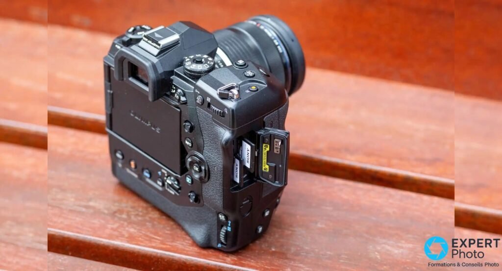 Olympus OM-D E-M1X vu de 3/4 arrière, trappe du double slot SD ouverte sur le flanc, deux cartes SD Sony visibles
