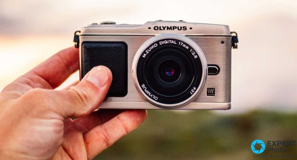 Olympus Pen E-P1 argent tenu en main, face avant, objectif M.Zuiko Digital 17mm f/2.8 monté