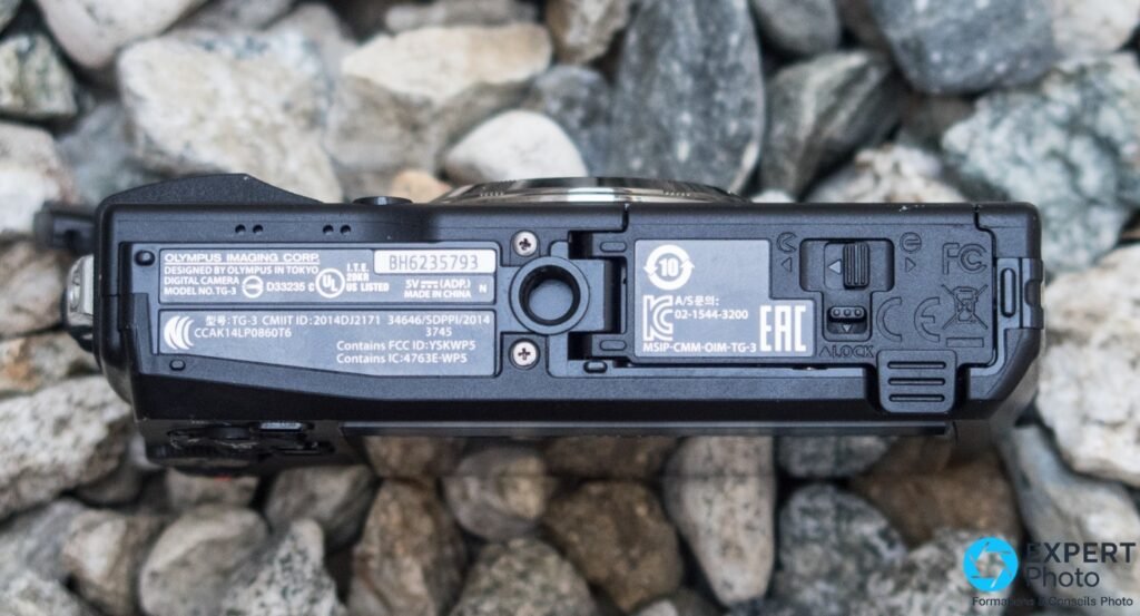 Dessous de l'Olympus Tough TG-3, étiquette « MODEL NO.TG-3 » et filetage de trépied central visibles, fond de galets