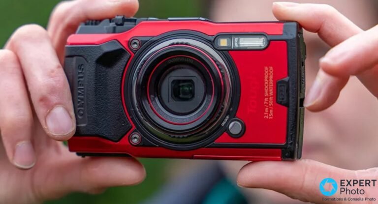 Olympus Tough TG-6 : ce que son successeur TG-7 change vraiment en 2026 TG-6 rouge tenu à deux mains, face avant, objectif zoom et bague rouge, marquages SHOCKPROOF WATERPROOF lisibles