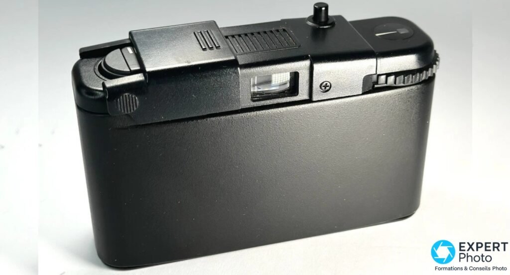 Olympus XA1 noir, vue 3/4 arrière gauche, fenêtre du viseur rectangulaire et molette de rembobinage dentelée visibles