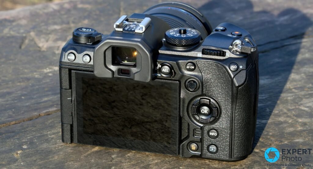 OM System OM-1 vue arrière posé sur pierre, écran inclinable visible, viseur électronique, boutons AEL AF-ON ISO OK
