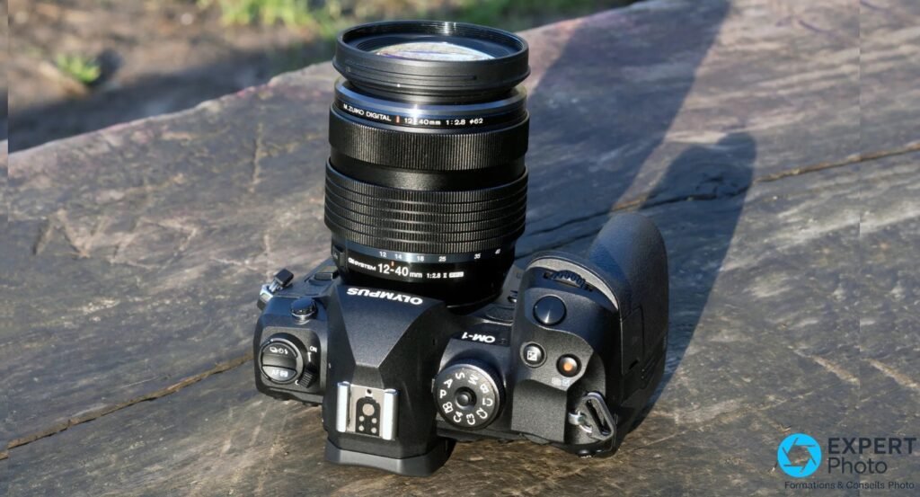 OM System OM-1 vue du dessus posé sur bois, objectif M.Zuiko Digital 12-40mm 1:2.8 II étendu, marquage lisible