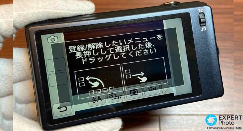 Panasonic DMC-3D1 tenu en mains gantées blanches, écran tactile avec menu japonais, sélecteur 3D/2D visible à droite