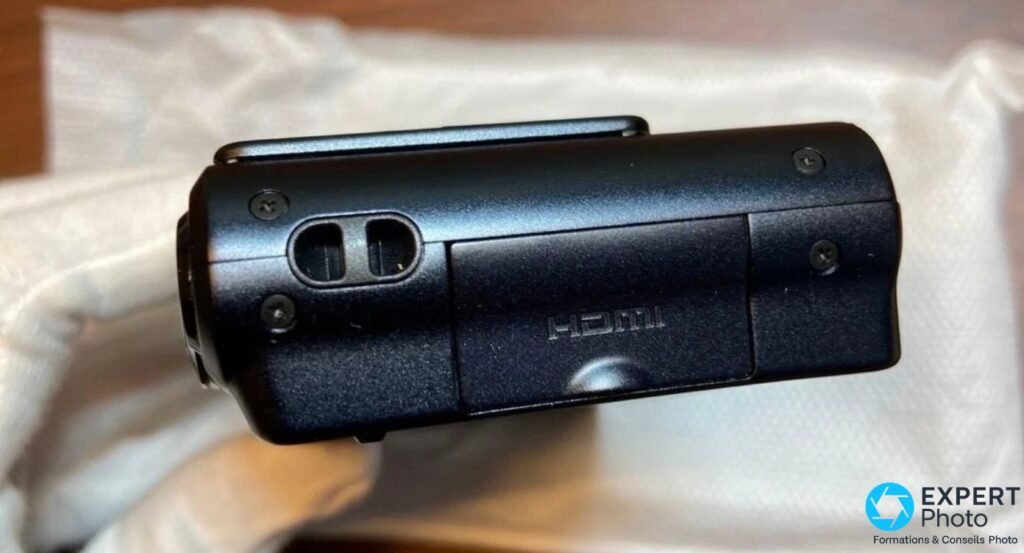 Tranche gauche Panasonic DMC-3D1, trappe connectique noire avec deux prises, marquage HDMI gravé sur la coque