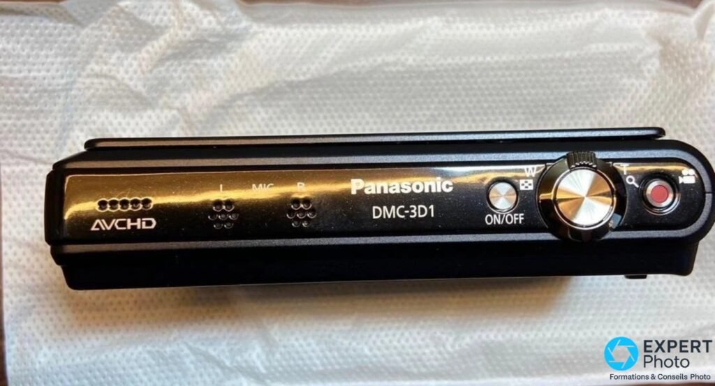 Panasonic DMC-3D1 tranche supérieure avec boutons ON/OFF, molette zoom, bouton vidéo rouge et micros AVCHD