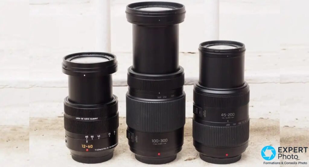 Panasonic Leica DG 12-60mm f/2.8-4 à gauche, avec deux zooms Micro 4/3 inscrits 100-300 et 45-200, devant mur blanc
