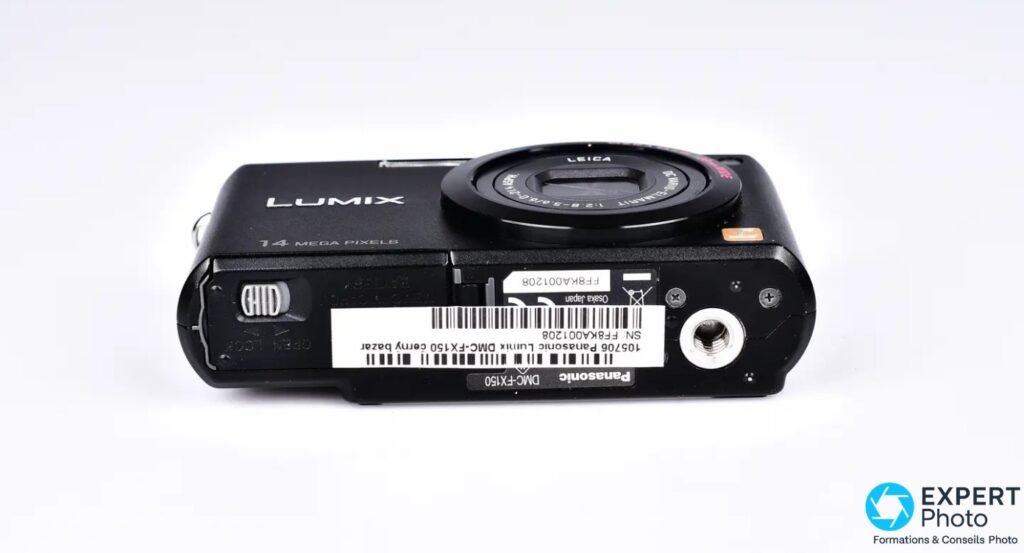 Panasonic Lumix DMC-FX150 noir, vue du dessous, étiquette constructeur avec code-barres, trappe batterie, curseur OPEN LOCK (