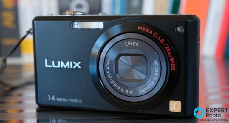 Panasonic Lumix DMC-FX150 noir, 3/4 avant gauche, objectif Leica rétracté, inscription LUMIX et 14 MEGA PIXELS, fond flou