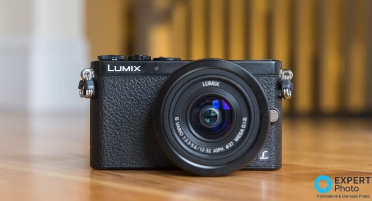 Panasonic Lumix GM1 noir face avant avec objectif 12-32 mm OIS monté, posé sur parquet, courroies visibles