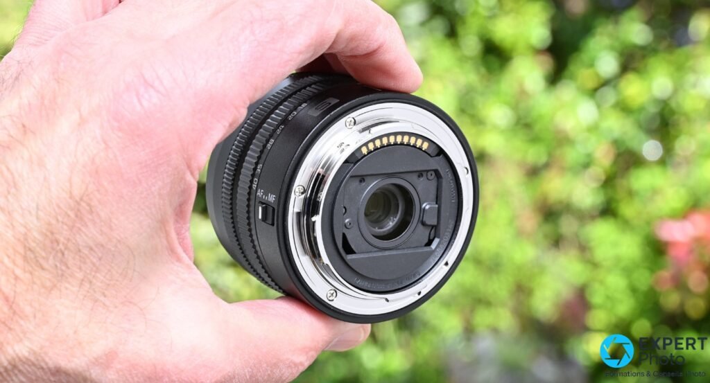 Monture arrière L-Mount du Lumix S 18-40mm, contacts dorés et élément optique arrière visibles, objectif seul tenu en main