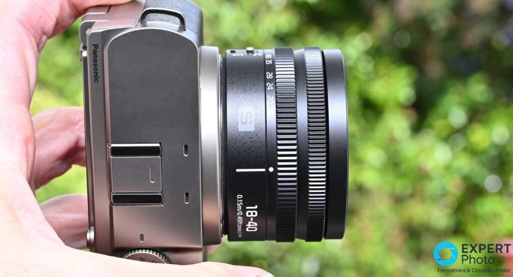 Lumix S 18-40mm sur boîtier Panasonic Lumix S, profil gauche, bague « 18-40 / 0.15m » lisible, tenu en main extérieur