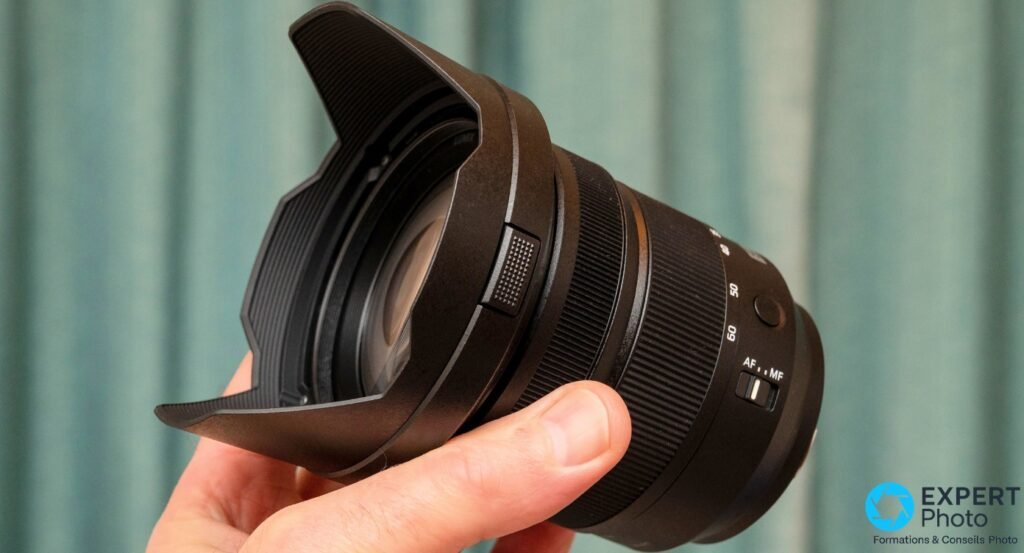 Objectif Panasonic Lumix S 24-60mm f/2.8 avec pare-soleil en pétales fixé, vue 3/4 avant, tenu en main